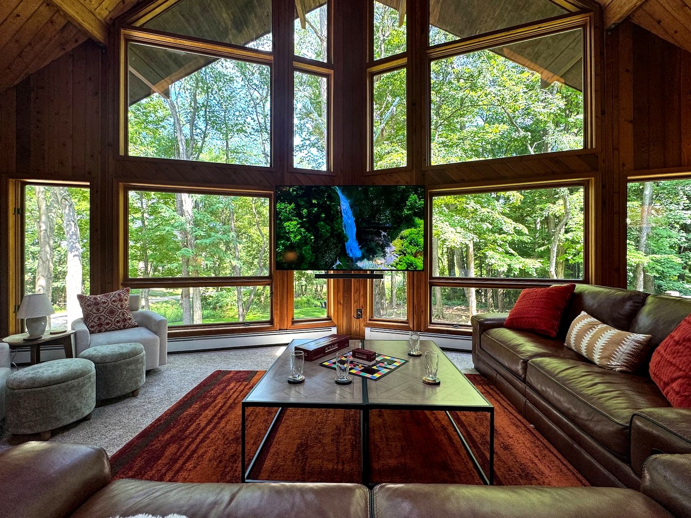Living room with floor-to-ceiling windows overlooking wooded lot